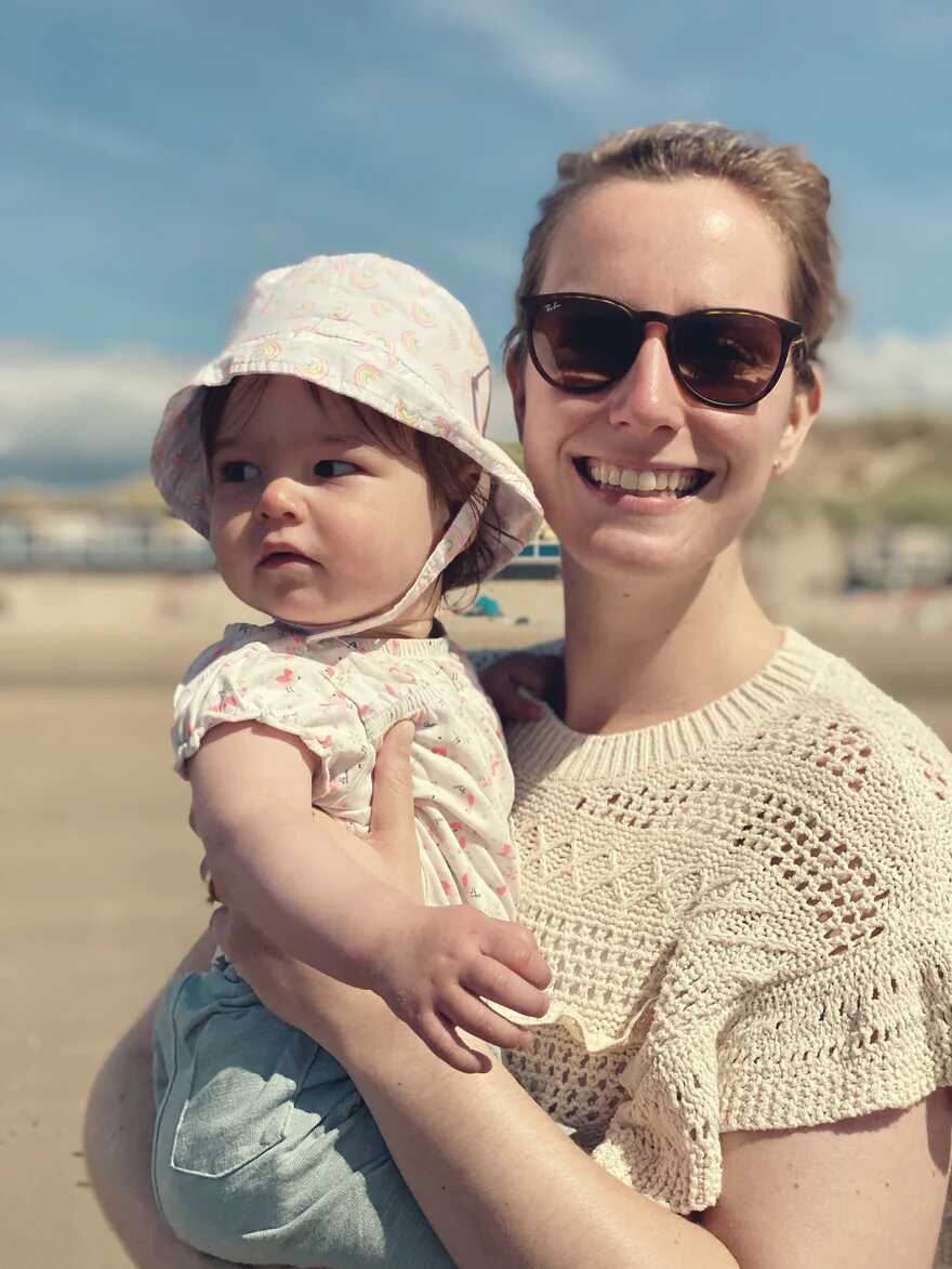 Ein Elternteil spielt liebevoll mit einem Baby auf einer Spieldecke